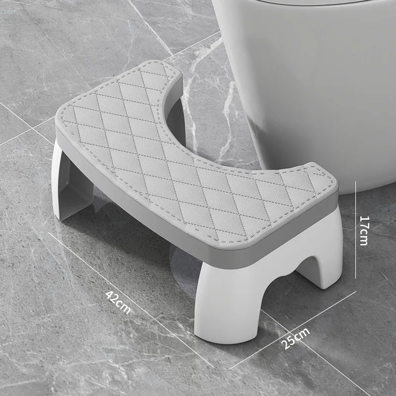 A gray ergonomic non-slip toilet squat stool with a diamond-patterned seat is shown on a tile floor.
