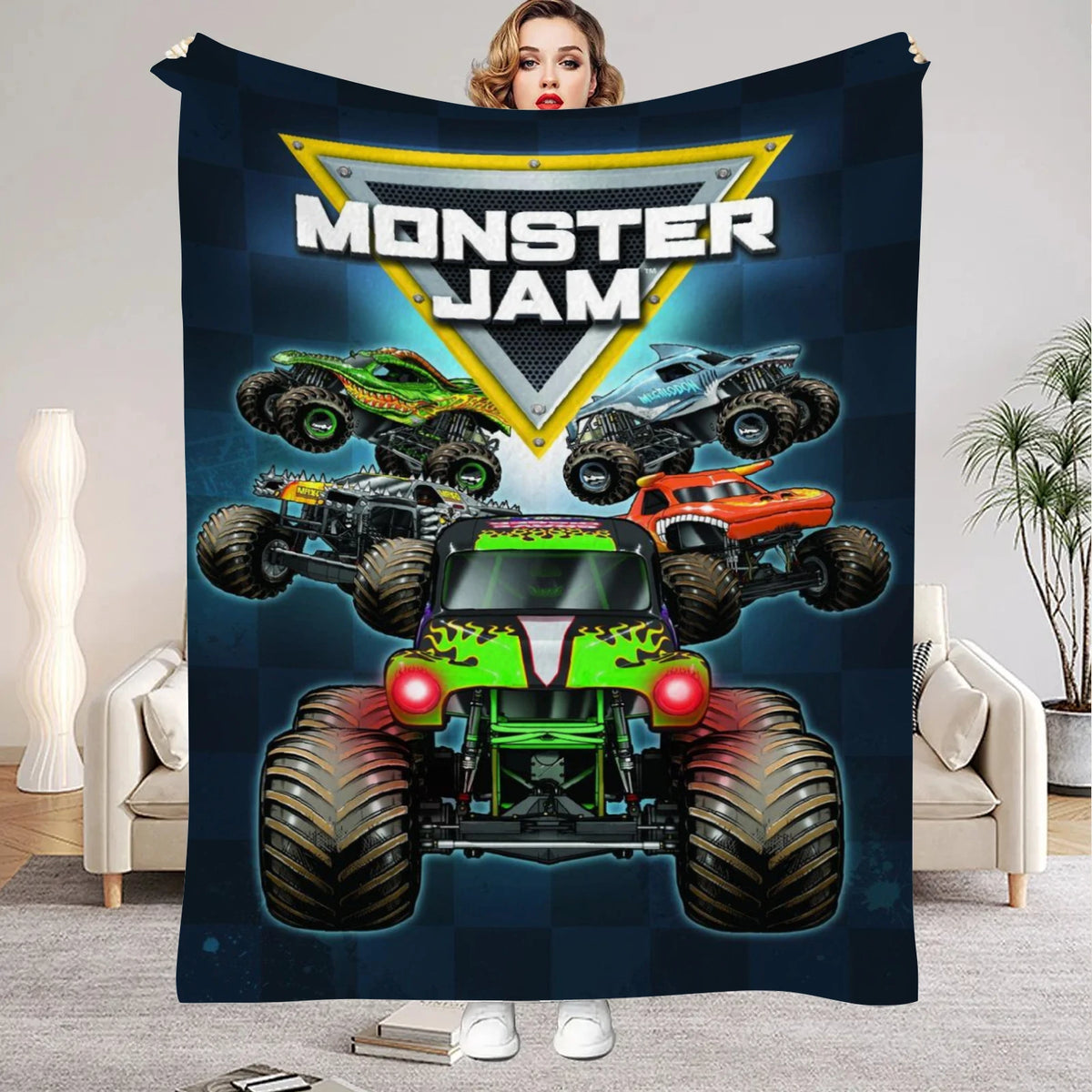 A dark blue blanket featuring a graphic of monster trucks under a yellow shield logo.