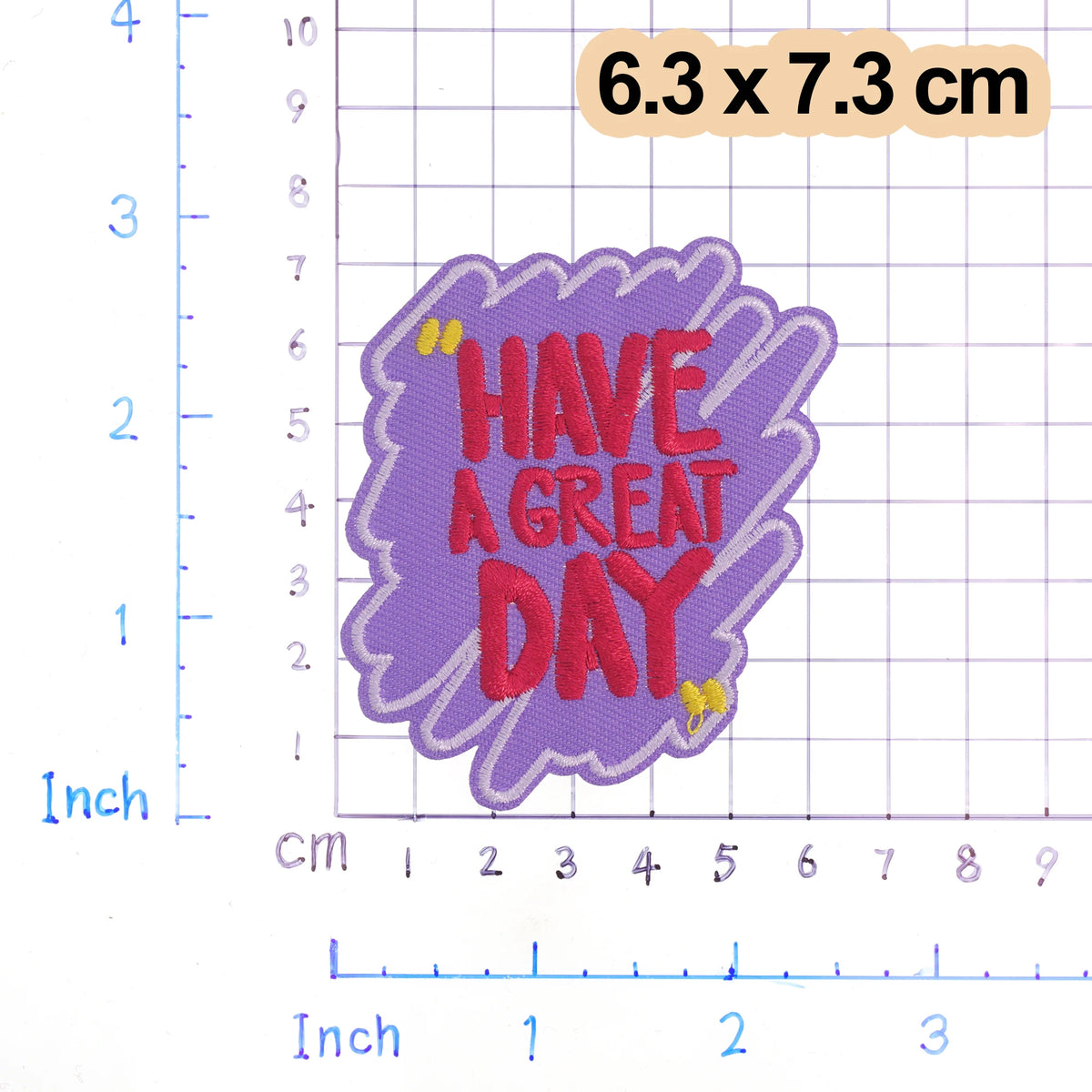 A purple embroidered patch with the text HAVE A GREAT DAY on it, measuring 6.3 x 7.3 cm.
