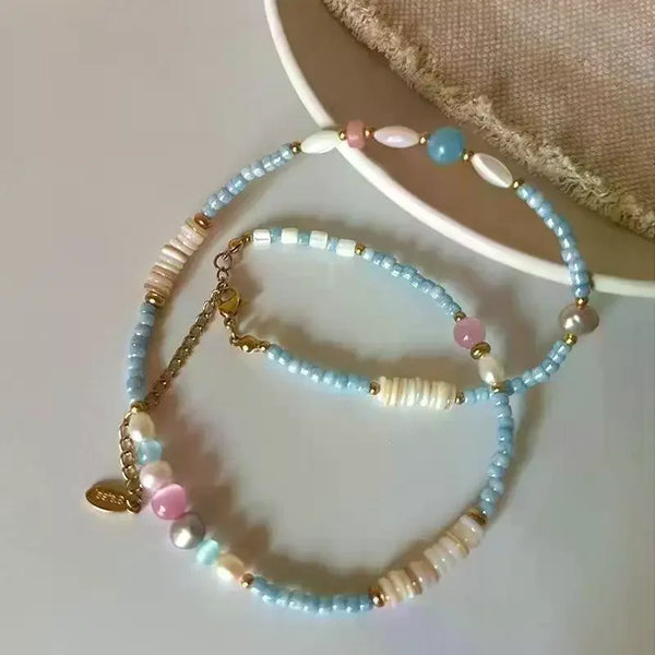 Un délicat collier col de cygne avec un mélange de pierres naturelles bleues et roses et de perles blanches.