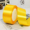 A roll of bright yellow satin ribbon used for gift wrapping or DIY crafts.