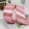 A roll of pink satin ribbon used for gift wrapping and DIY crafts.