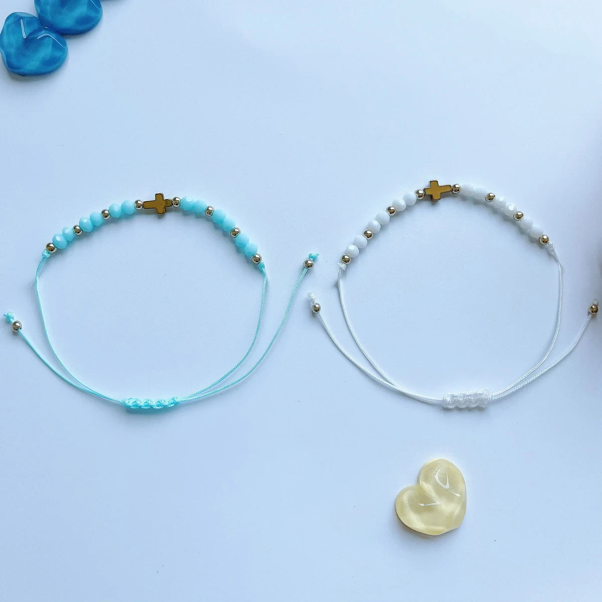 Un couple de bracelets perlés bohèmes, un turquoise et un blanc, présentés sur une surface bleu clair.