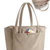 A beige structured laptop tote bag with convertible straps shown next to a stack of folded bags.