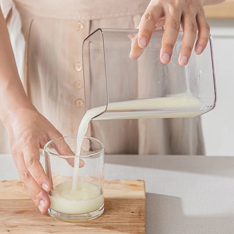 A hand pours yogurt from a stainless steel strainer into a glass bowl.