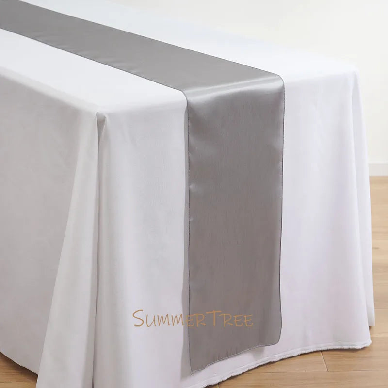Elegant satin table runner in gray and white on a white tablecloth.