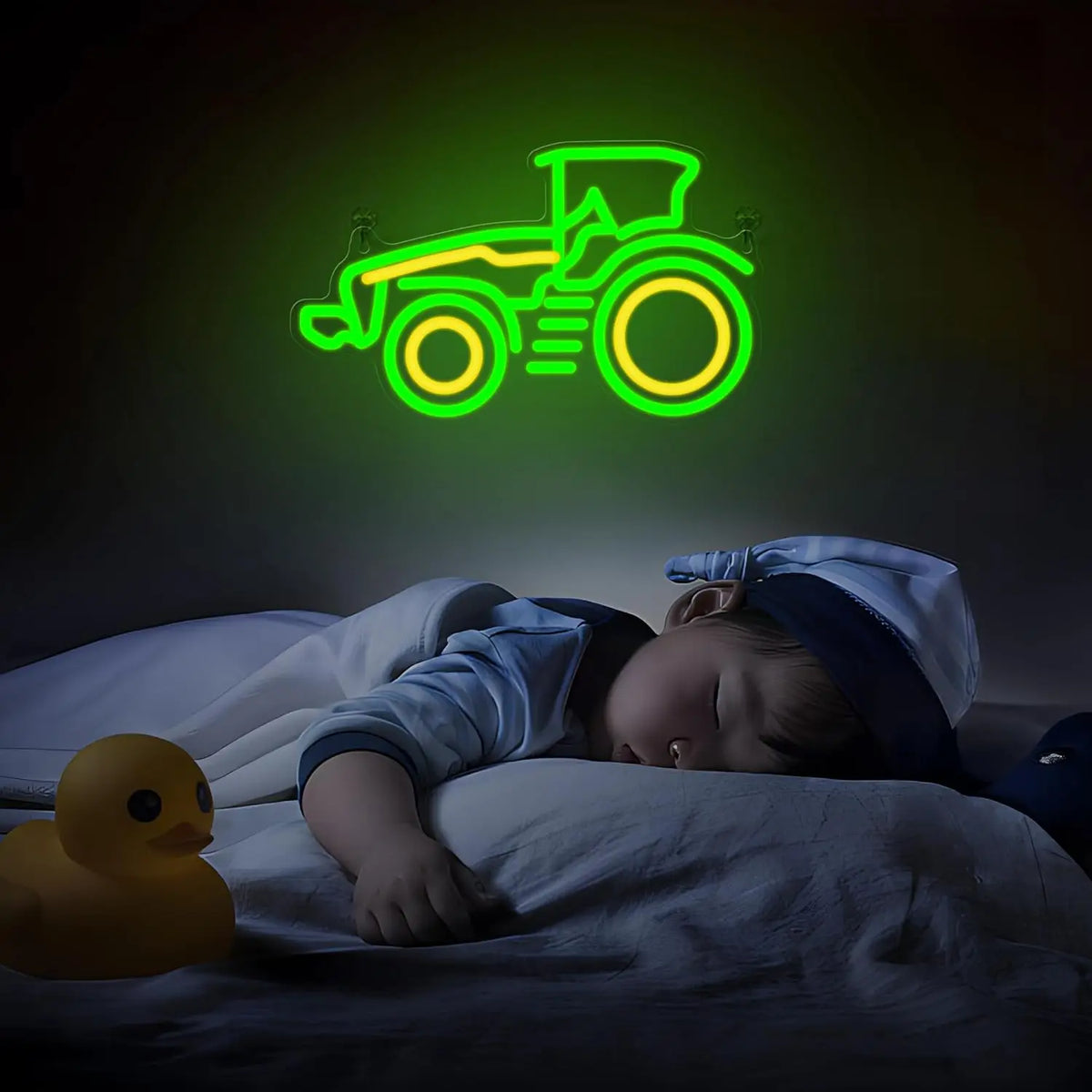 A neon sign shaped like a tractor in green and yellow glows against a dark background next to a sleeping baby.