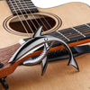 A close-up of a guitar fret with a shark-design capo made of zinc alloy resting on the wood.