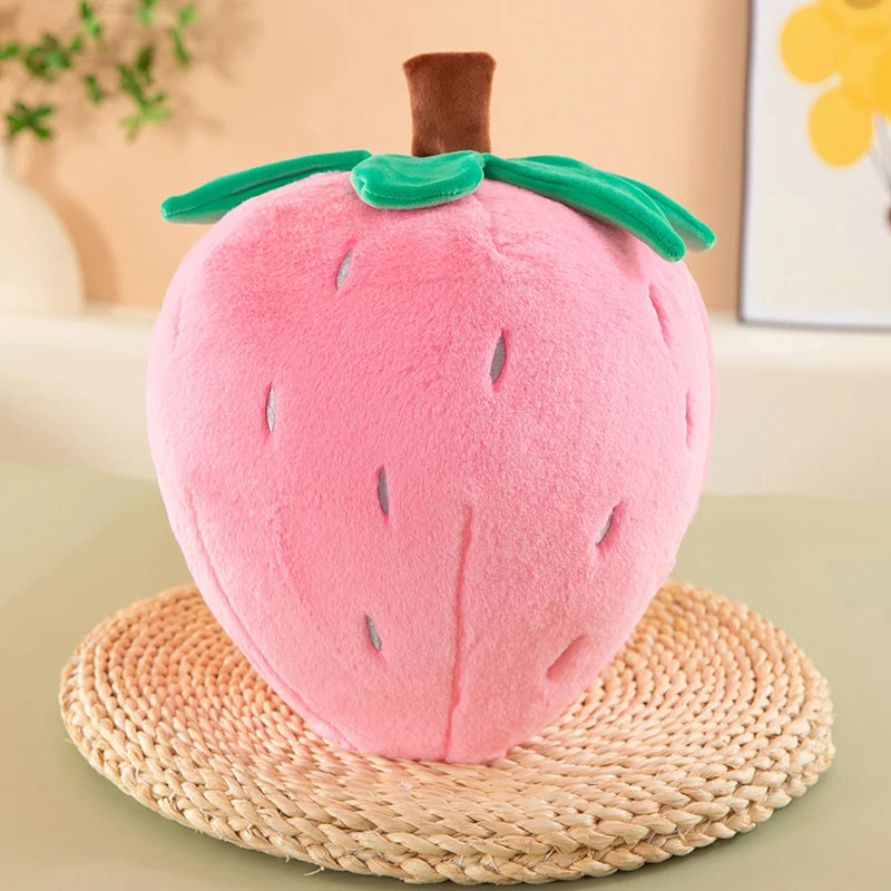 A pink strawberry plush throw pillow resting on a woven mat.