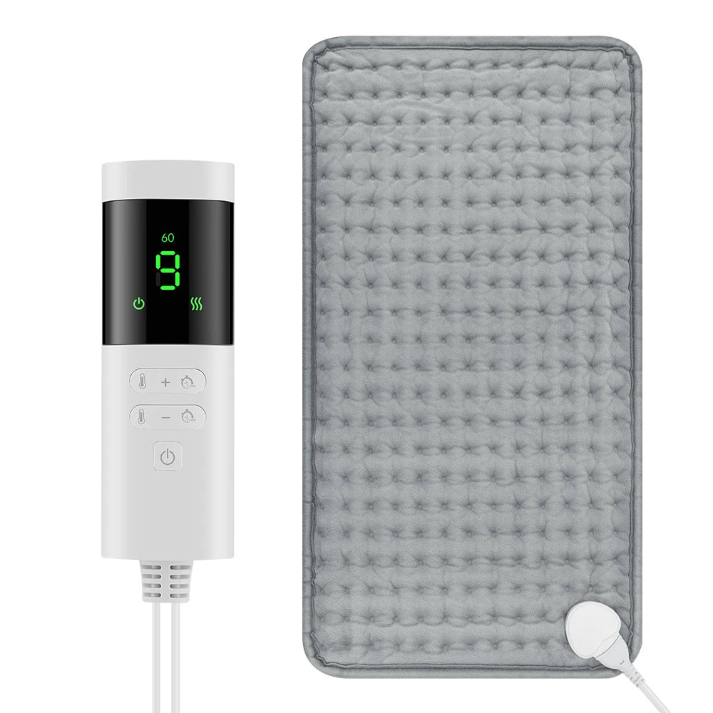 A white electric heating pad with a digital display and controls is shown against a gray textured surface.