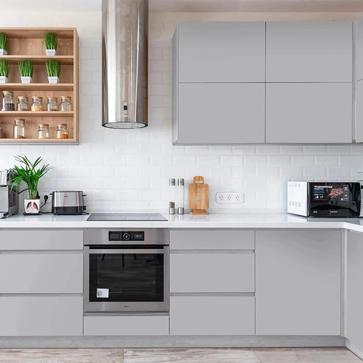 Modern kitchen cabinet and wall unit featuring matte gray cabinetry, white subway tile backsplash, and stainless steel hood.