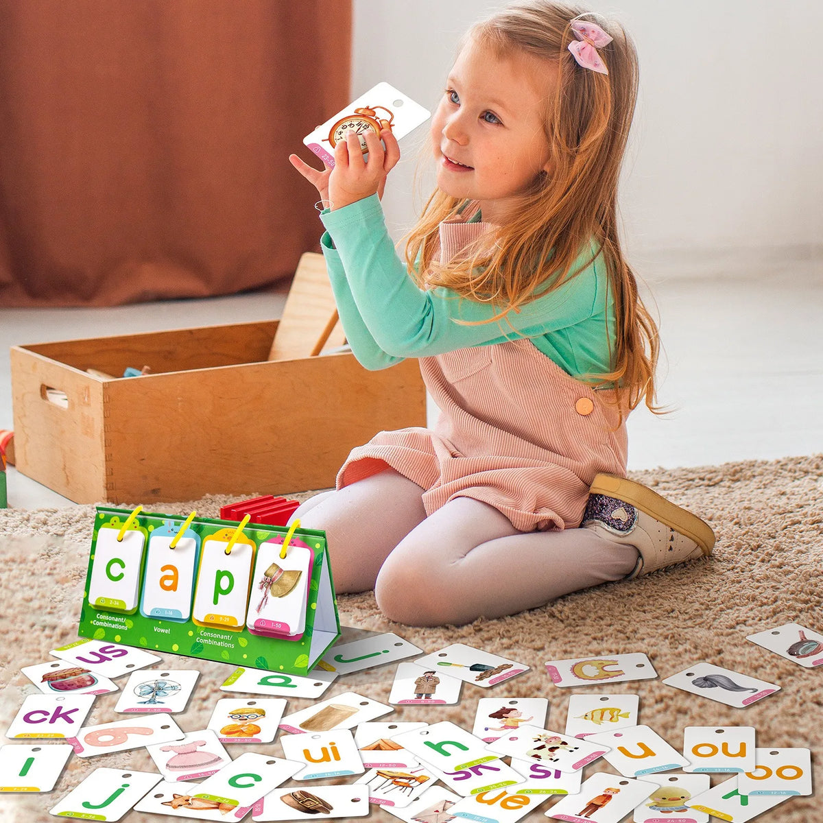 A young girl is holding and examining cards with letters and words on them, demonstrating English learning.