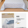 A light blue floral quilted bedspread with a white border is displayed on a bed in a bedroom setting.