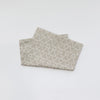 A stack of soft cotton baby pillowcases featuring a geometric cartoon pattern in beige and white.
