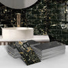Stack of black and gold marble self-adhesive wall stickers used as 3D tile decals for kitchen and bathroom decor