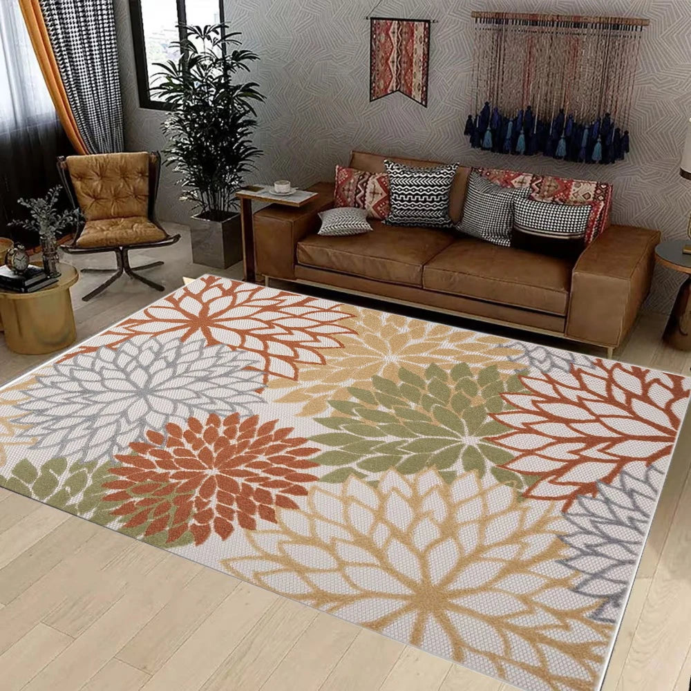 A rectangular outdoor area rug featuring a geometric pattern in shades of terracotta, olive green, beige, and gray.