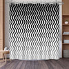 Black and white wavy stripe shower curtain hanging on a rod