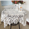 White lace tablecloth with embroidered rose design set on a table.