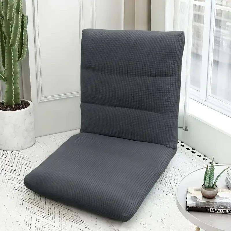 A dark gray foldable floor sofa cover for a single seat or lounger placed on a white floor.