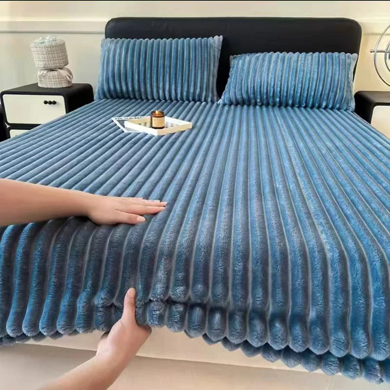 A close-up of a blue knitted fitted bed sheet draped over a dark bed with matching pillows.