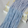 A close-up of a long strand of light blue silver tassel string curtain hanging next to a white box.