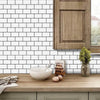 A white subway tile backsplash with a wooden cabinet and a bowl of eggs on a light wood countertop.