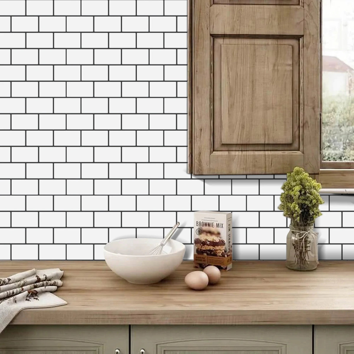 A white subway tile backsplash with a wooden cabinet and a bowl of eggs on a light wood countertop.