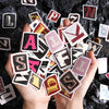 A hand holds a collection of vintage alphabet stickers on a dark surface.