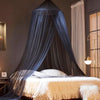 A dark blue ceiling-hung dome mosquito net draped over a bed, featuring sheer fabric and a single door.