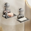 A silver wall-mounted soap dish with a suction cup holder and drain is installed on a beige wall.