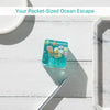 A small, translucent blue glass squeeze toy filled with colorful ocean-themed beads rests on a white wooden surface.