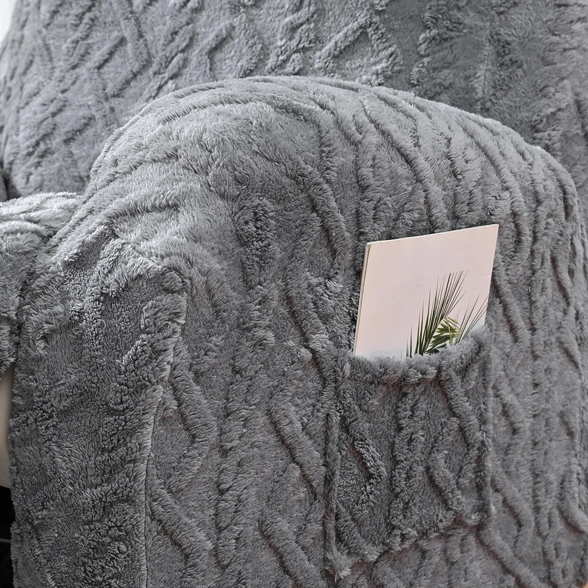 Gros plan d'une housse de canapé en fausse fourrure grise avec un motif tricoté texturé et une petite carte insérée dans le t