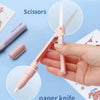 A hand holds a pink mini pen-shaped scissor and paper knife tool on a light blue background.