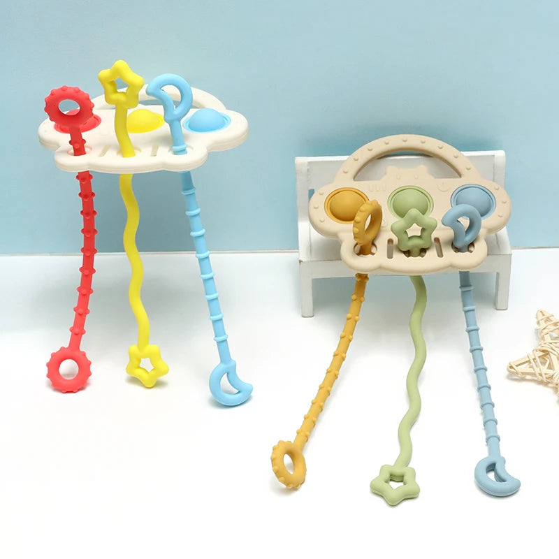 A set of silicone bear teethers with textured pull strings in red, yellow, and blue colors.