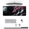 Un tapis de souris noir avec une silhouette d'arbre de cerisier rose sur fond sombre.