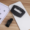 A black portable digital luggage scale is shown resting on a white surface next to a scale measuring tape.