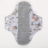 Reusable cotton menstrual pads featuring a light gray background with floral patterns and a solid gray absorbent core.