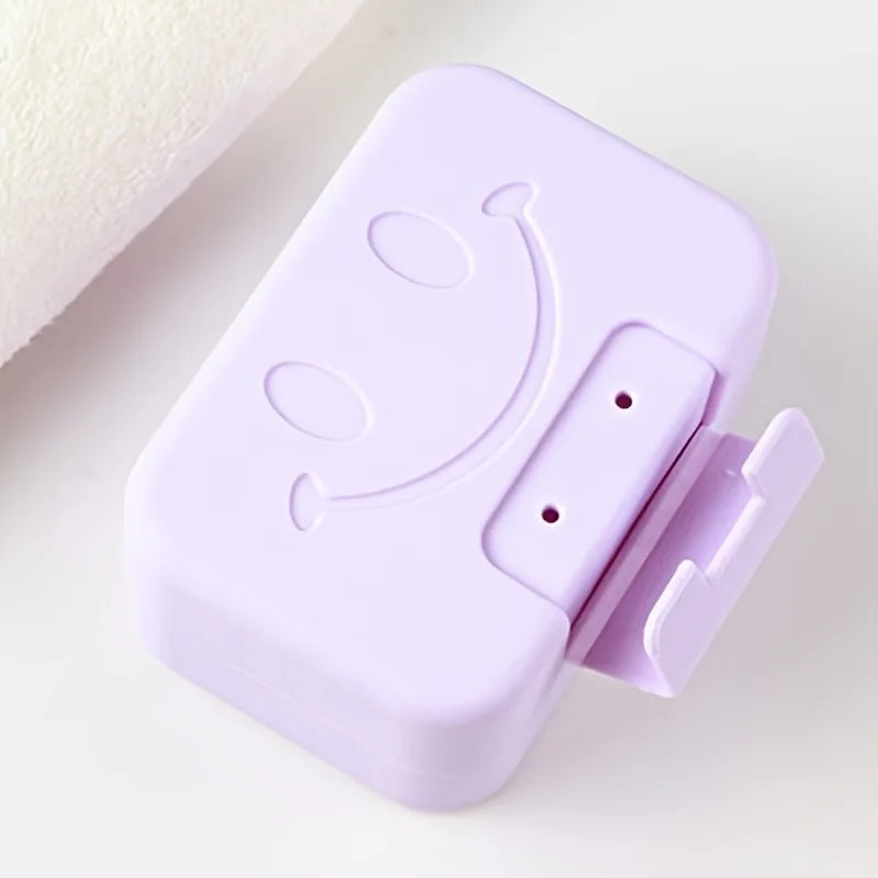 A purple smiley face lidded soap dish for bathroom and travel, shown in a close-up view.