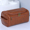 A brown leather toiletry bag with gold zippers resting on a white sink.