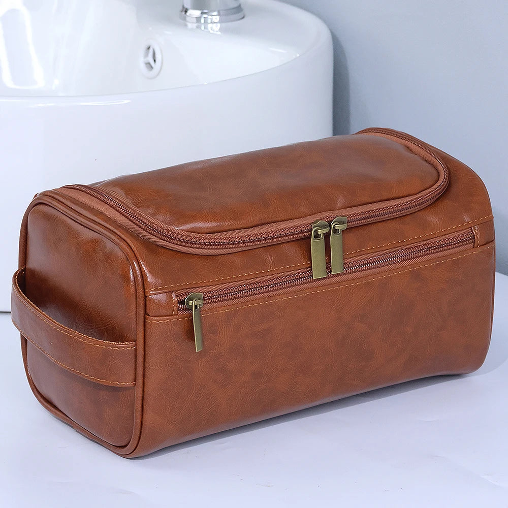 A brown leather toiletry bag with gold zippers resting on a white sink.