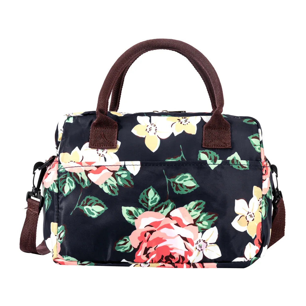 A black insulated picnic lunch bag with a floral pattern and brown cross-body straps.