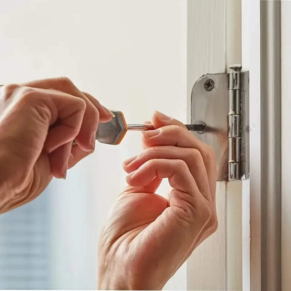 A person's hands are installing a door latch using a metal tool on a white window frame.