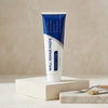 A tube of Wall Repair Paste is shown standing on a light wooden block with a small brush and scraper nearby.
