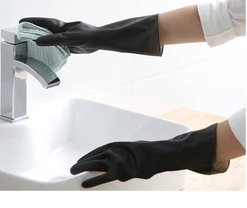 A hand wearing a black rubber cleaning glove is shown gripping a faucet in a white sink.