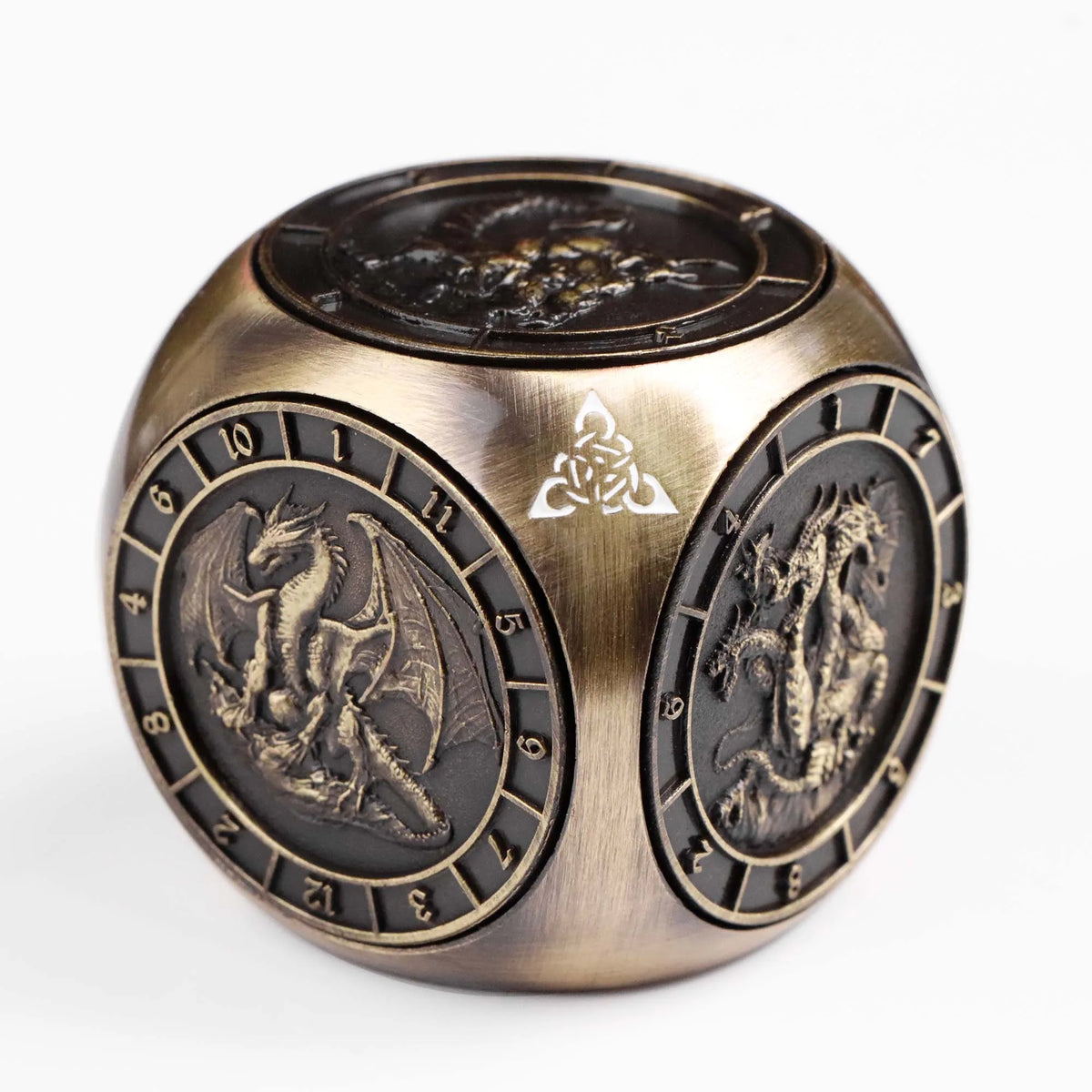 A bronze metal spinner dice cube featuring embossed dragon designs and a triquetra symbol.