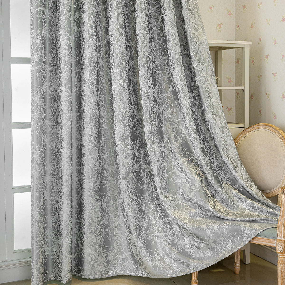 Gray tree bark jacquard blackout curtain panel draped next to a light wood chair.