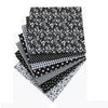 A bundle of black and white cotton fabric squares featuring various floral, dot, and checkered patterns for patchwork.