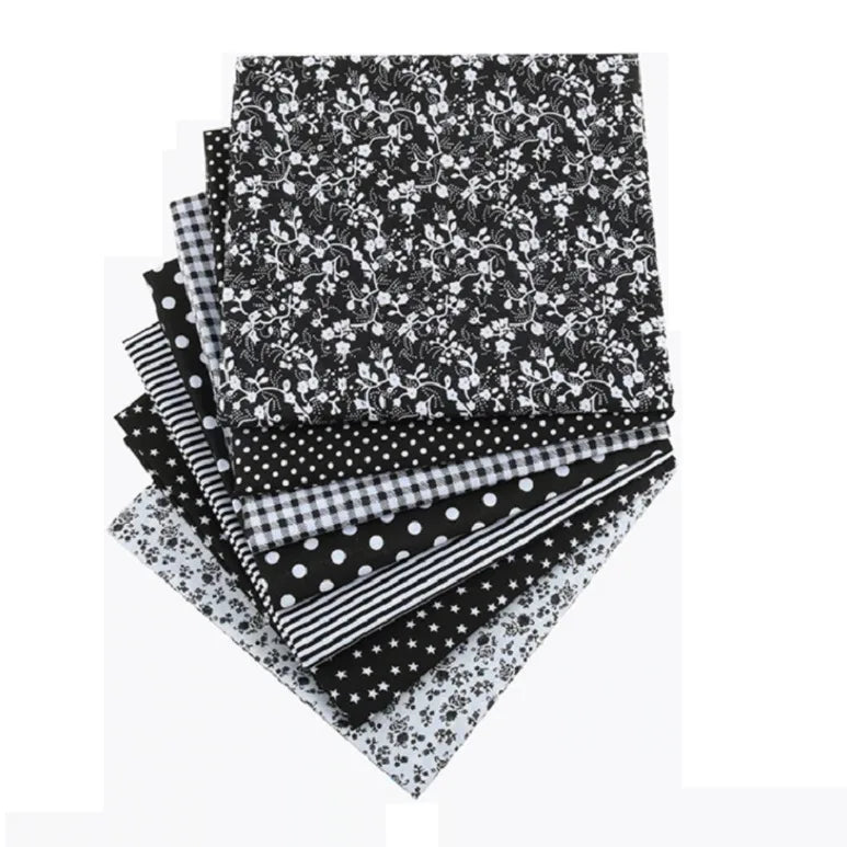 A bundle of black and white cotton fabric squares featuring various floral, dot, and checkered patterns for patchwork.