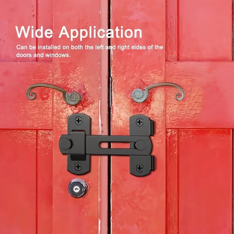 A close-up of a black stainless steel flip barn door lock installed on a red wooden door.