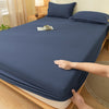 A dark blue fitted sheet is draped over a bed, showing its soft texture and elastic edge.